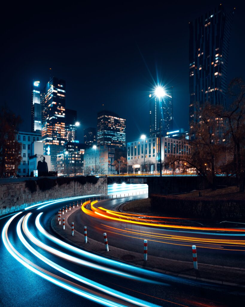 Home Long exposure of dynamic traffic lights against Warsaw's illuminated skyline at night.
