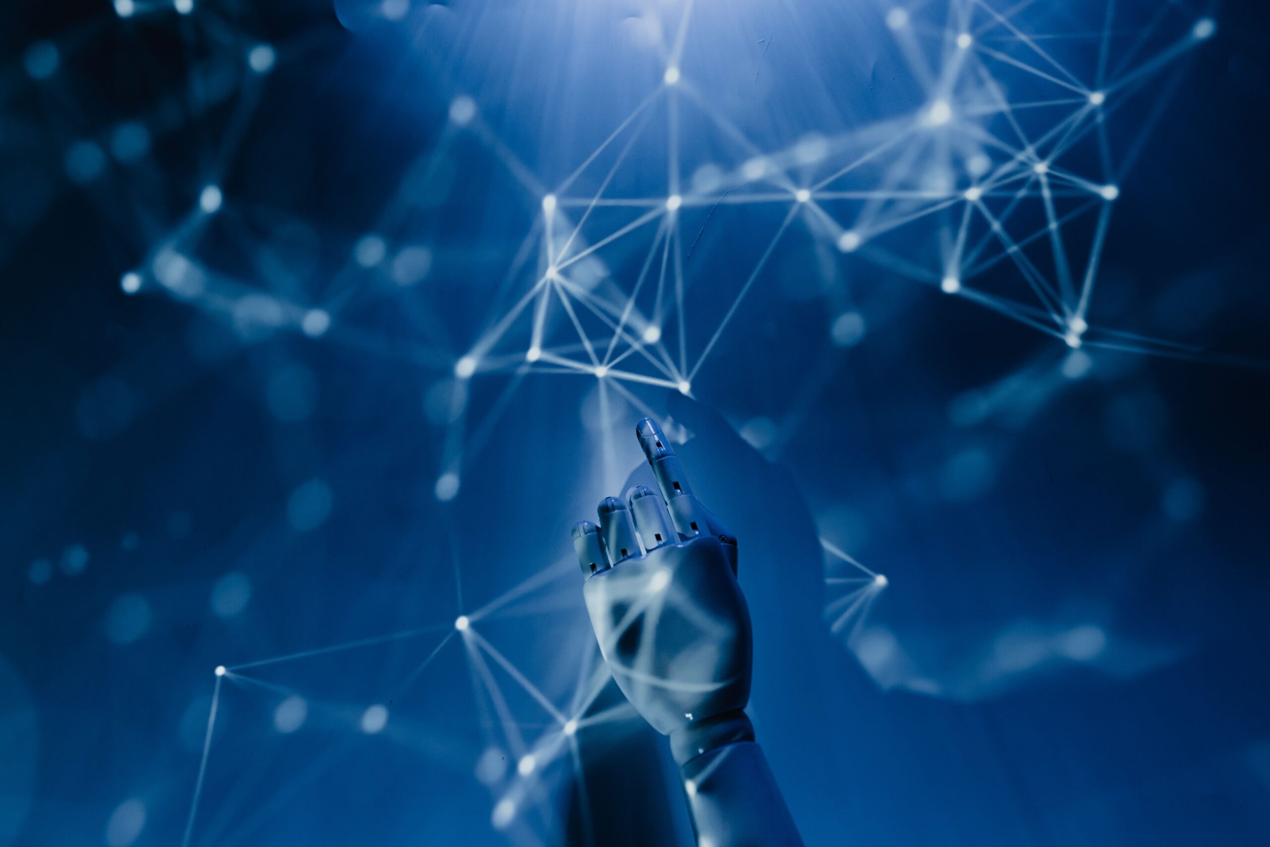 About A robotic hand reaching into a digital network on a blue background, symbolizing AI technology.